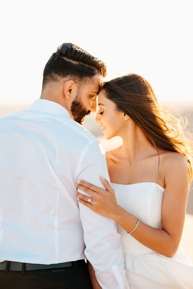 a bride and groom embracing each other on the beach