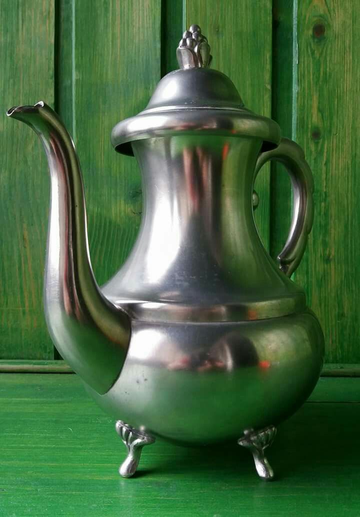 a silver tea pot sitting on top of a green table