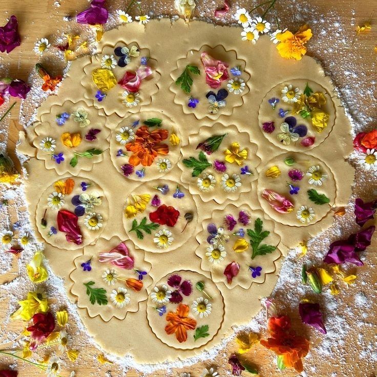 a cookie with flowers on it sitting on top of a wooden table covered in powdered sugar