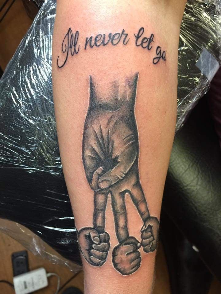 a black and white tattoo with an image of two hands holding each other