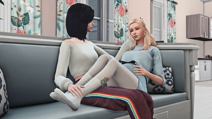 two women are sitting on a couch talking to each other