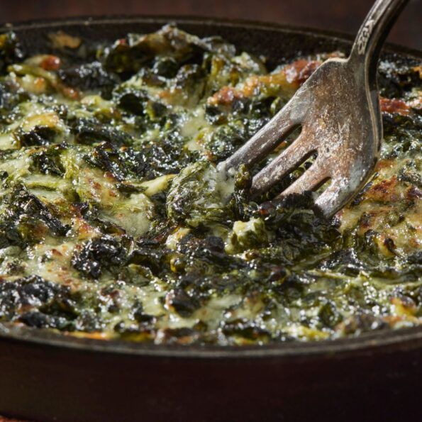 a spatula is being used to stir spinach and cheese in a skillet