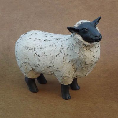 a white and black sheep figurine sitting on top of a brown tablecloth