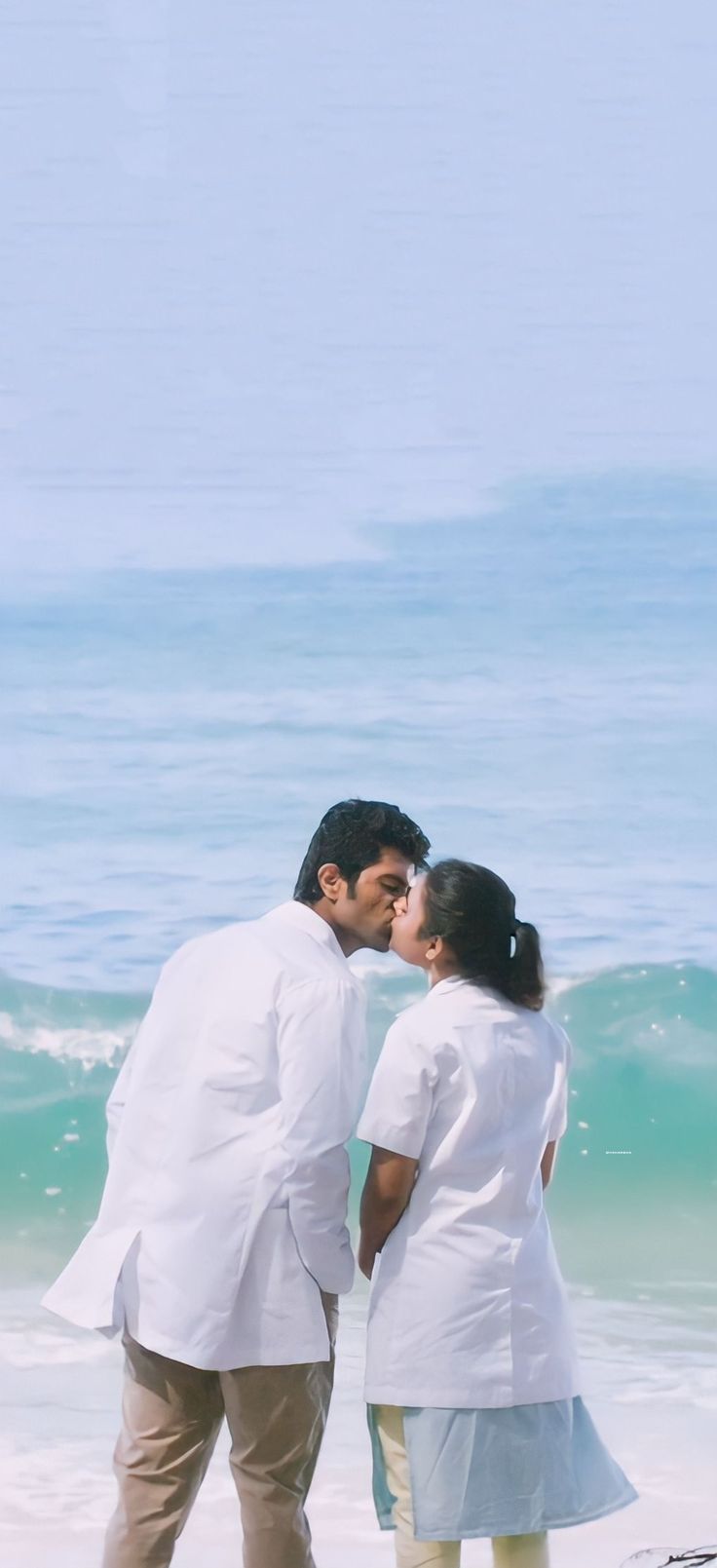 a man and woman kissing on the beach