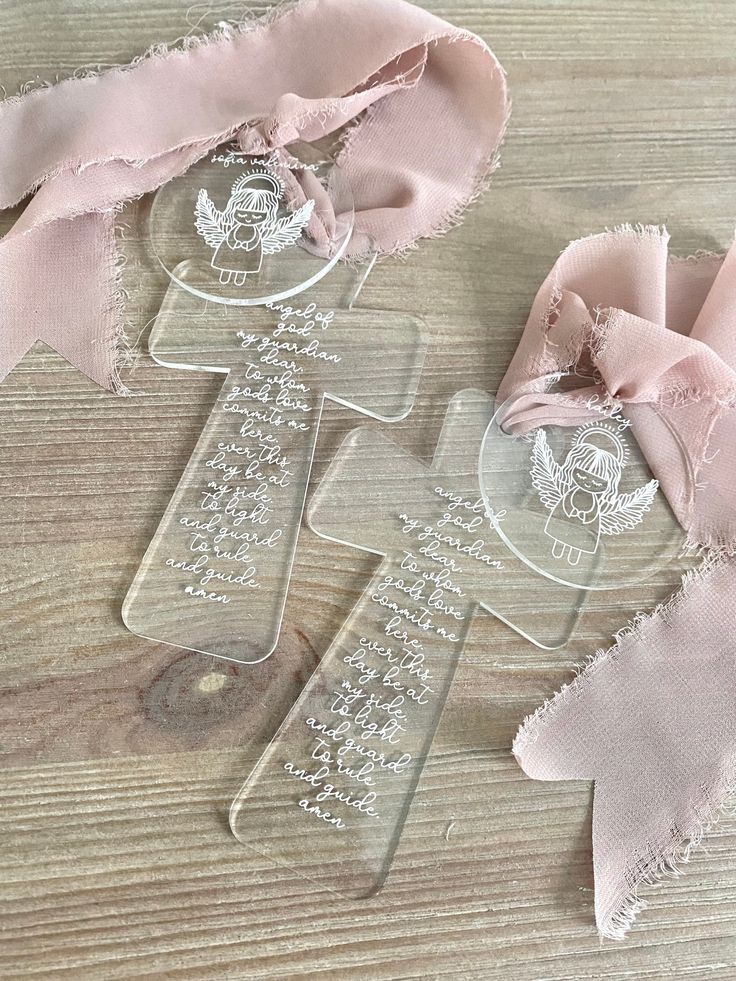 two pieces of glass with pink ribbon on top of a wooden table next to each other