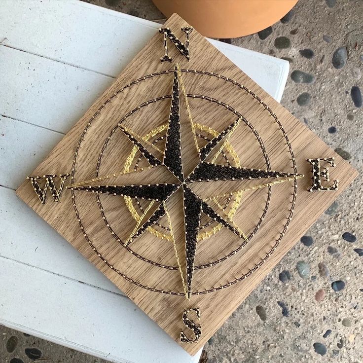 a wooden plaque with a gold and black design on it sitting on a table next to a potted plant