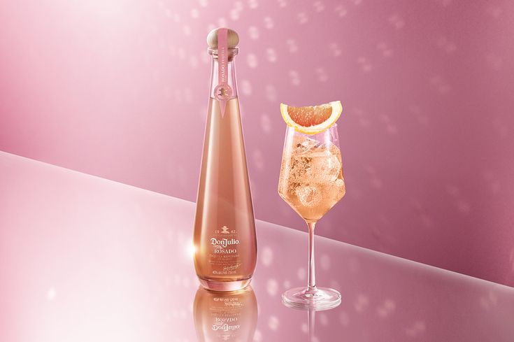 a bottle of sparkling wine next to a glass filled with ice and orange wedges