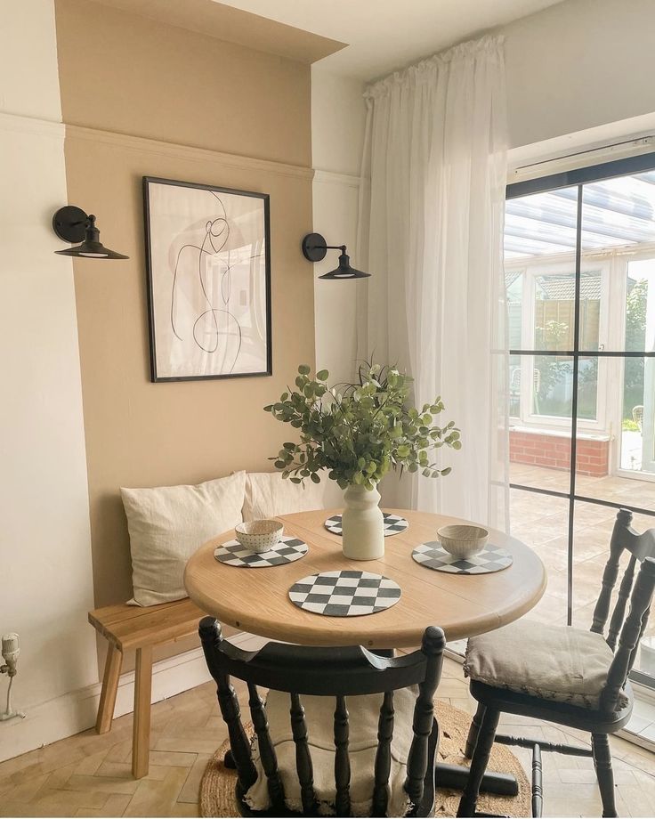 a dining room table with two chairs and a potted plant