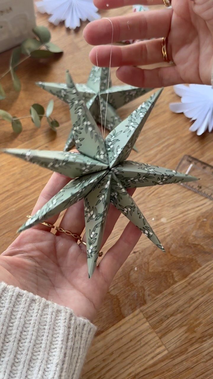 a person is holding an origami star in their hand on a wooden table