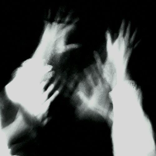 blurry photograph of two hands reaching towards each other