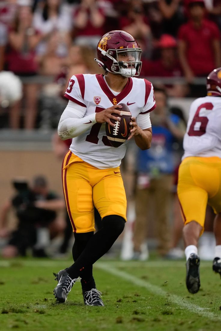 a football player holding a ball on top of a field with other players in the background