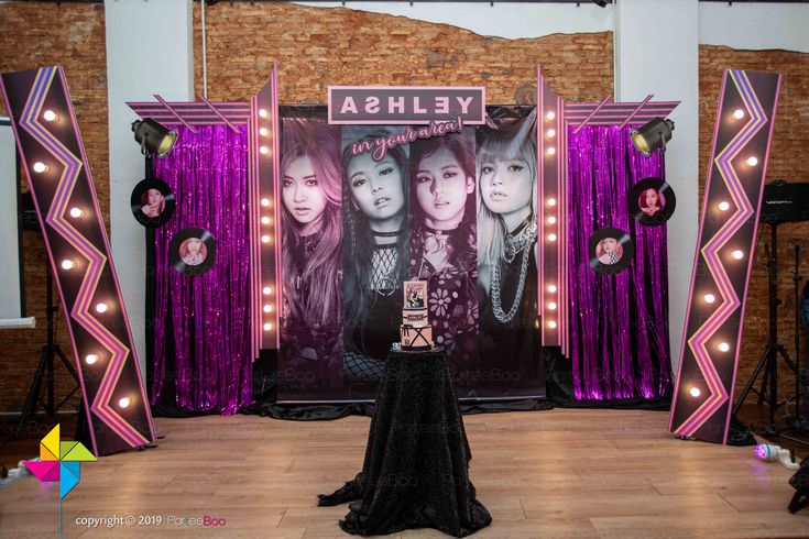 the stage is set up for an event with purple curtains and lights on it, as well as two women in black dresses