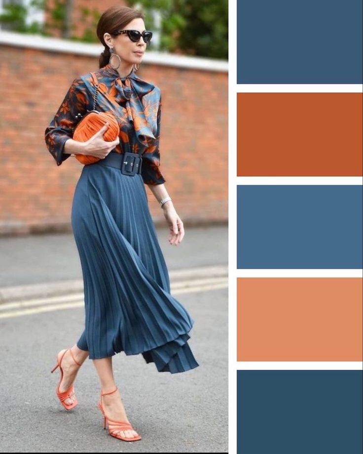 a woman walking down the street wearing a blue dress and orange shoes with an orange purse