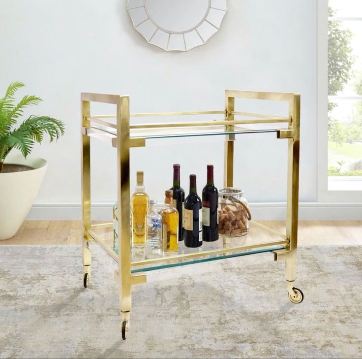 a gold bar cart with bottles of wine and liquor on it in a living room