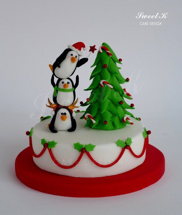 a cake decorated with two penguins and a christmas tree