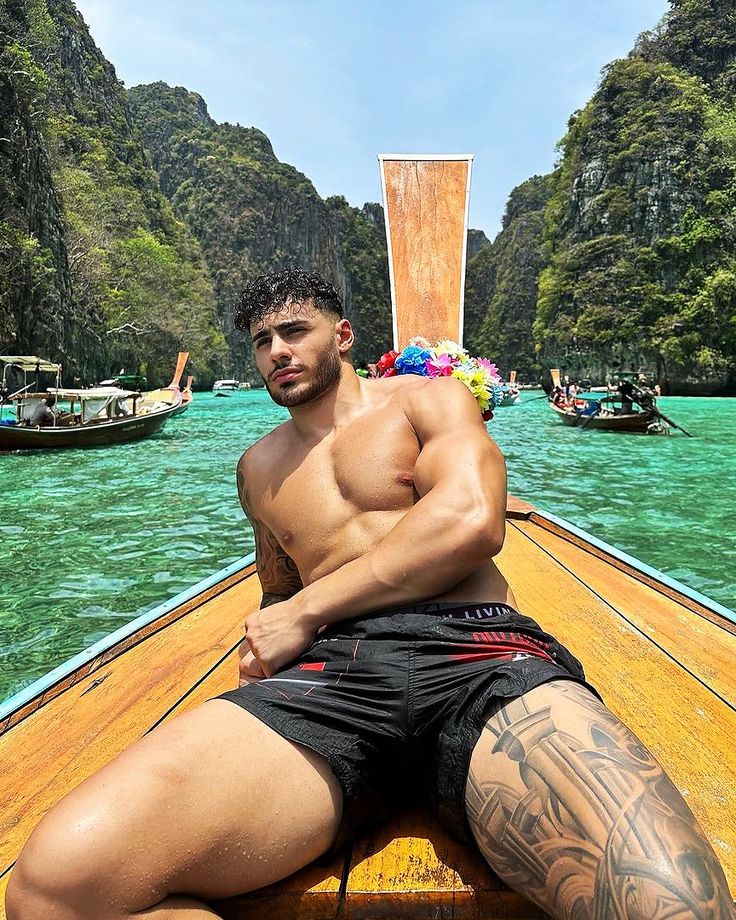 a shirtless man sitting on the back of a boat