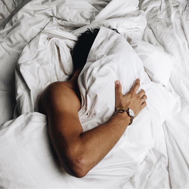 a man laying in bed with white sheets