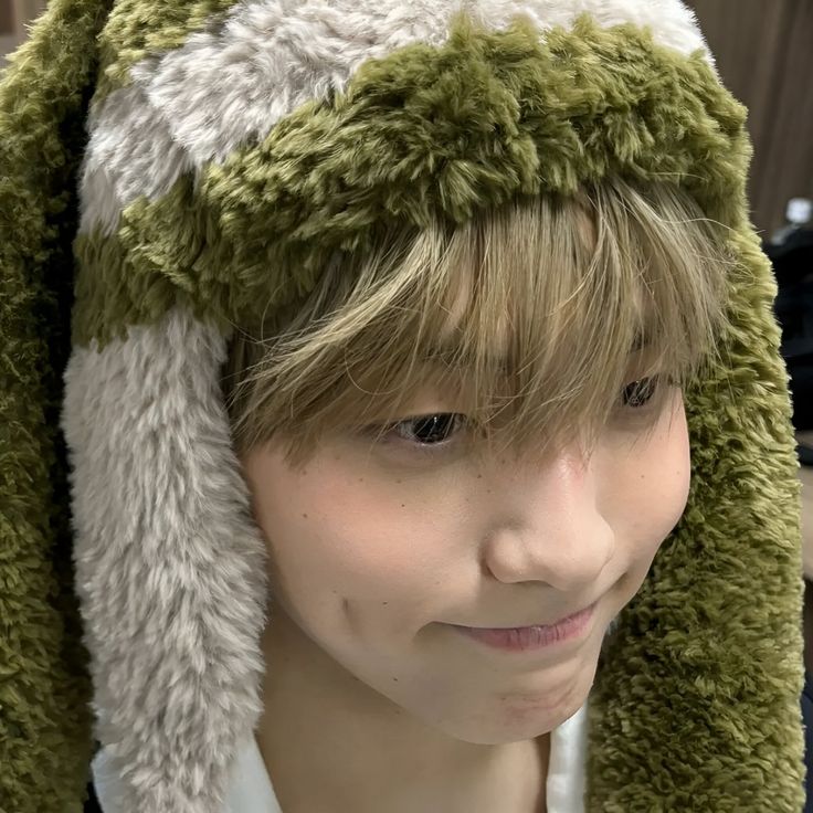 a young man wearing a green and white furry hat with ears folded over his head