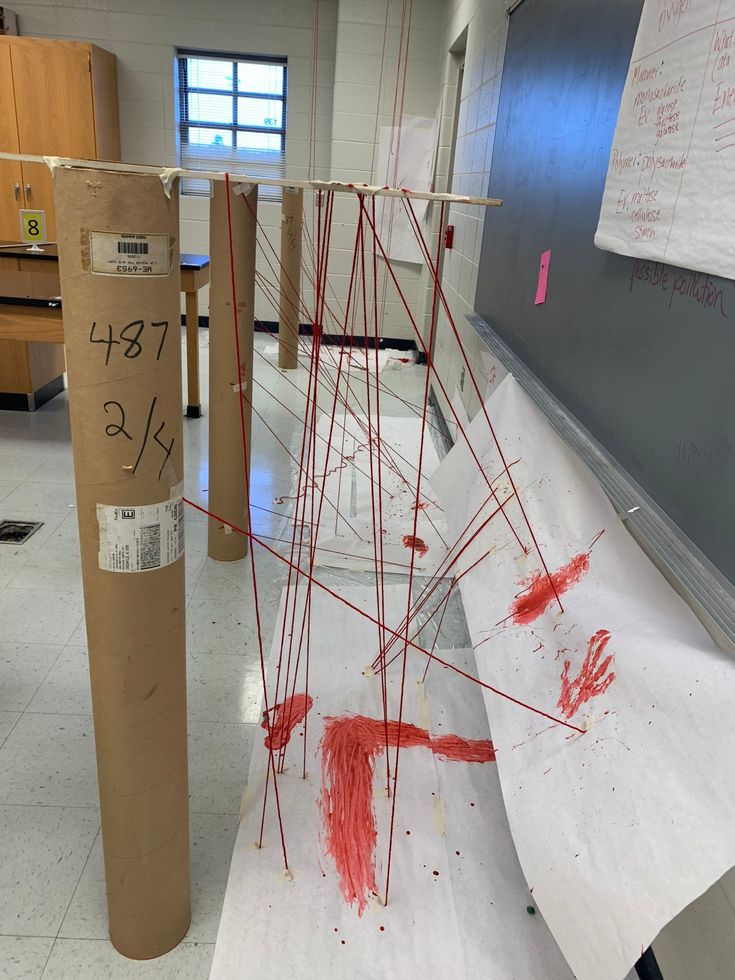 an art project is being made with cardboard and red paint on the floor in a classroom