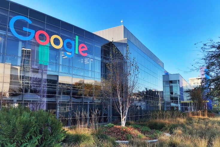 an office building with the google logo on it's glass front wall and trees