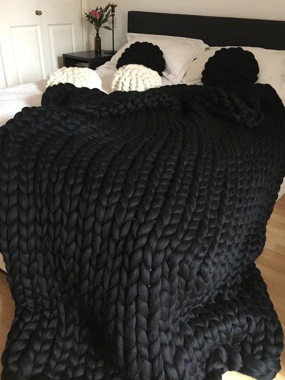 a large black blanket sitting on top of a bed