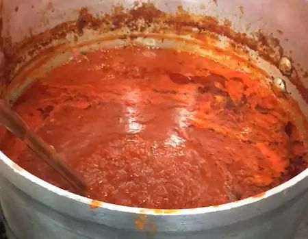 a large pot filled with red sauce on top of a stove