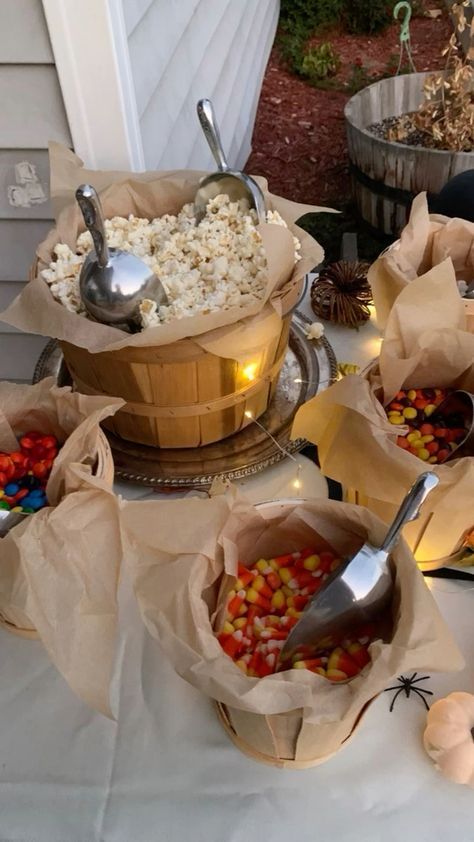 several baskets filled with popcorn and candy corn on top of a white cloth covered table