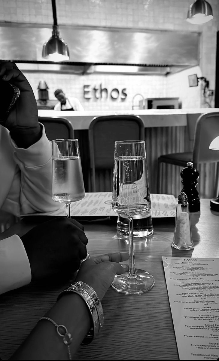 two people sitting at a table with wine glasses