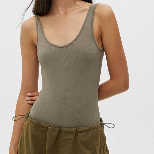 a woman is wearing a tank top and khaki shorts with her hands on her hips