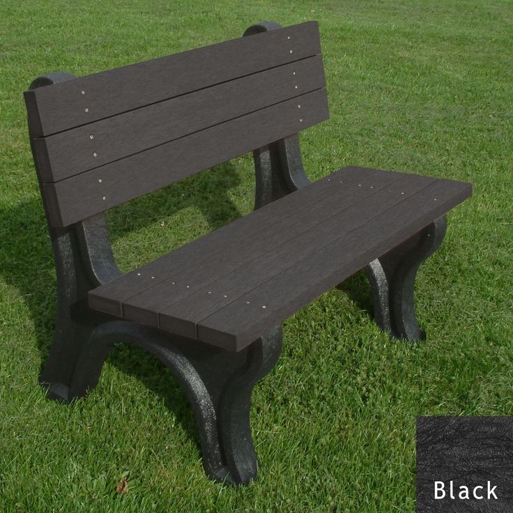 a park bench sitting on top of a lush green field next to a black trash can