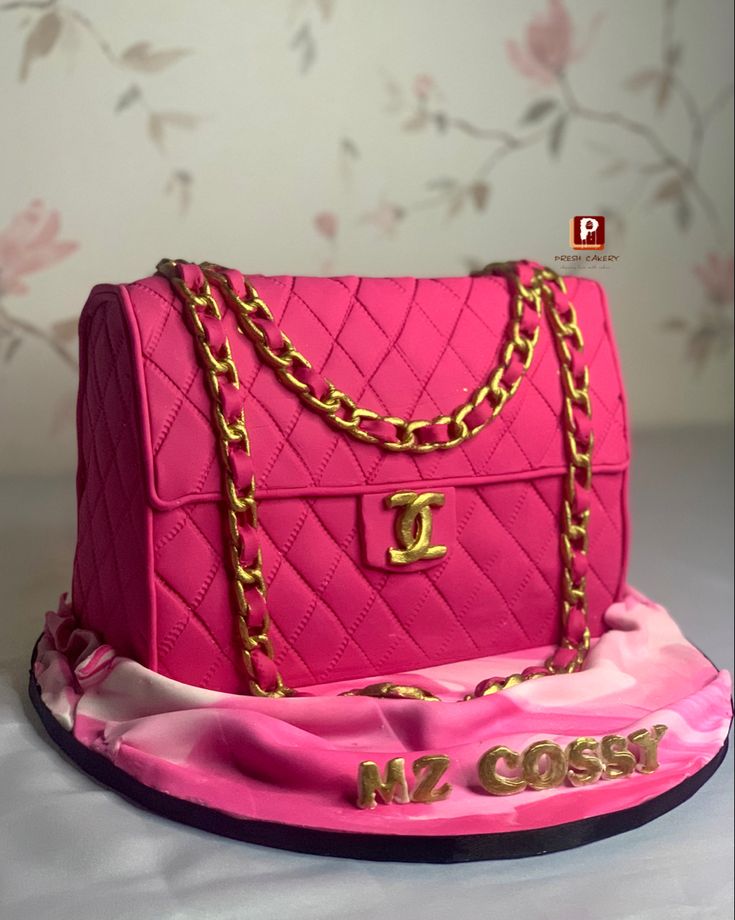 a pink purse cake with gold chains on it