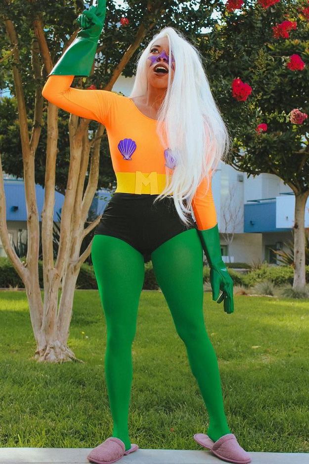 a woman dressed in an orange and green costume is posing for the camera with her arms outstretched