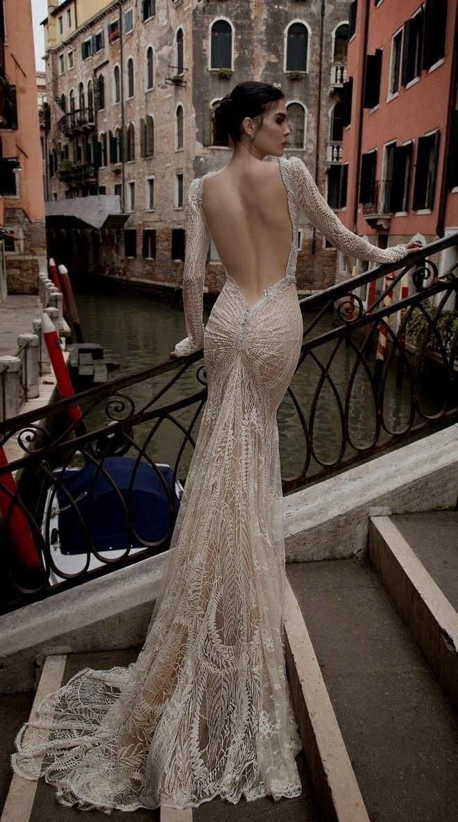 a woman in a dress standing on some steps looking down at the water and buildings