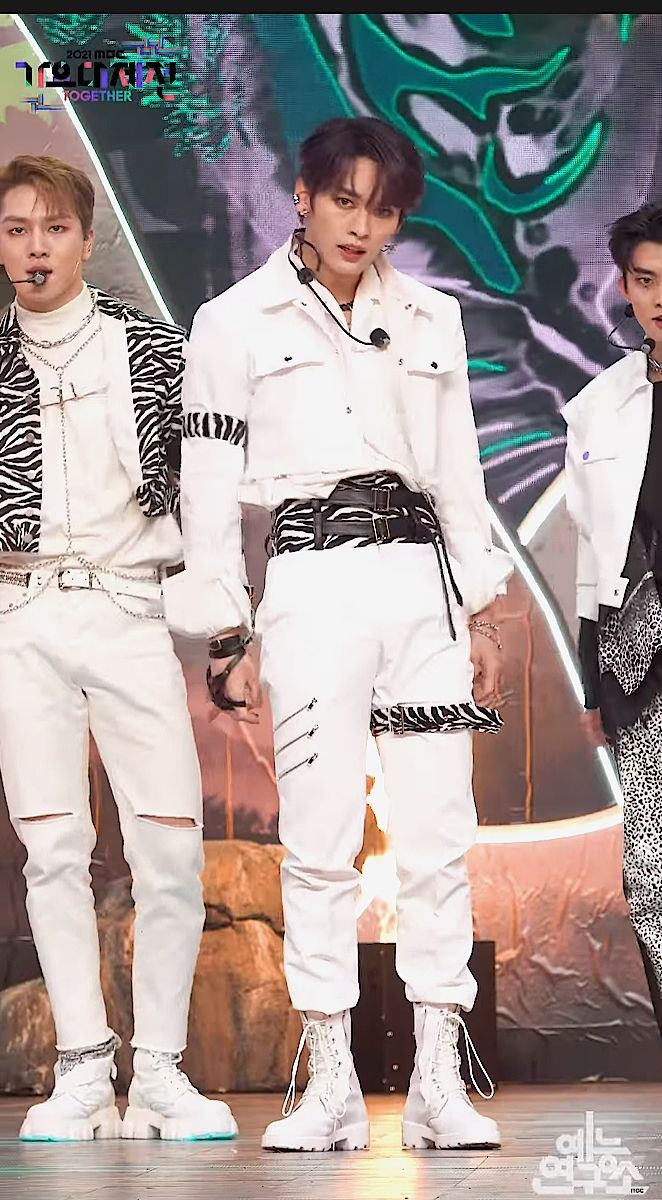 three young men standing on stage with one wearing white pants and the other black shirt