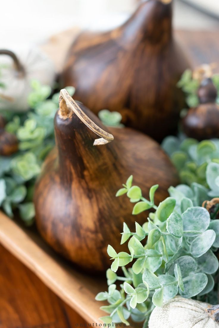 some figurines sitting on top of a wooden tray filled with plants and rocks