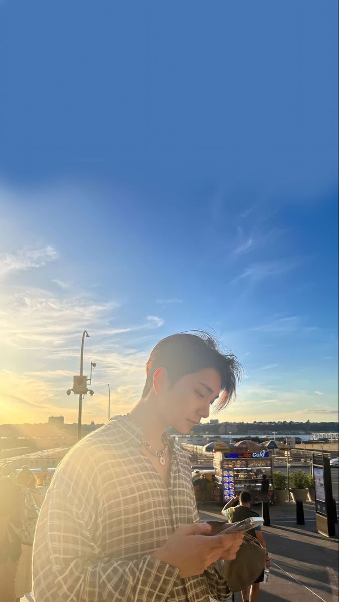 a man standing next to the ocean looking at his cell phone