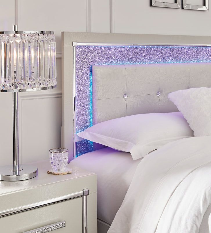 a white bed topped with pillows and a night stand next to a nightstand filled with lights