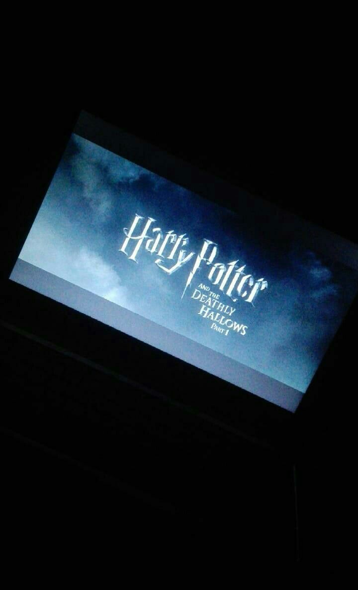 the logo for harry potter is projected on a large screen in the dark, with clouds behind it