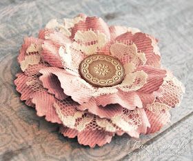 a pink flower brooch sitting on top of a wooden table next to a button