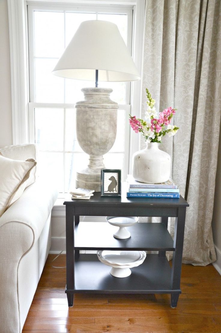 a living room with a couch, table and lamp on it's side by the window