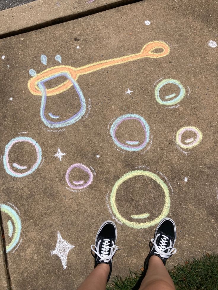 someone is standing on the sidewalk with chalk drawings