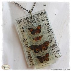 a glass pendant with butterflies on it is hanging from a chain that has writing all over it