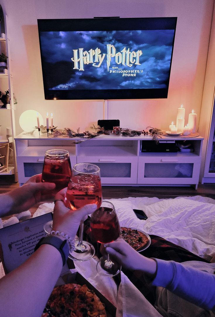 two people toasting with wine glasses in front of a harry potter sign on the screen