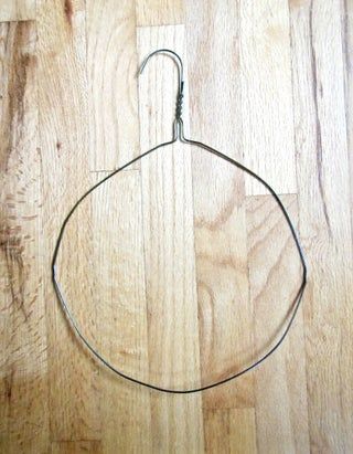 a piece of metal wire on a wooden floor with a hook in the middle that is attached to it