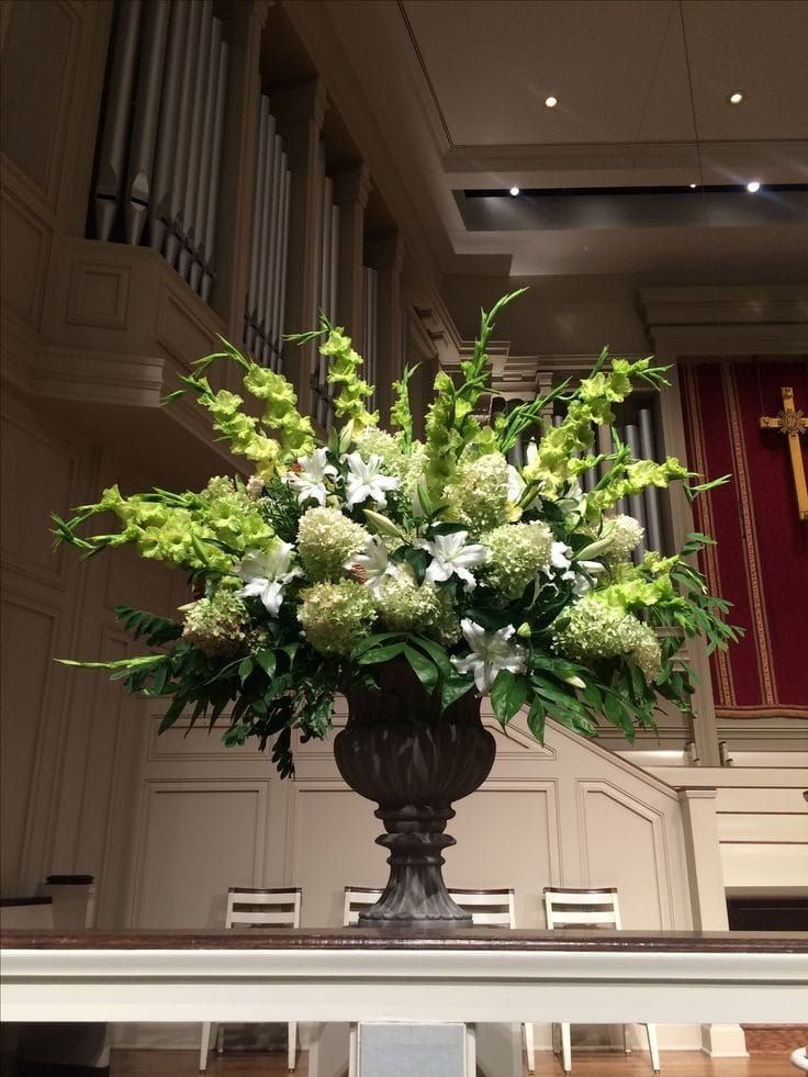 a large vase filled with lots of flowers on top of a table in front of a pipe organ