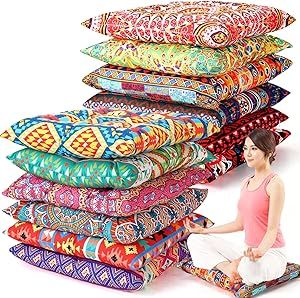 a woman sitting on the ground next to a stack of colorful cushions and pillows in different colors