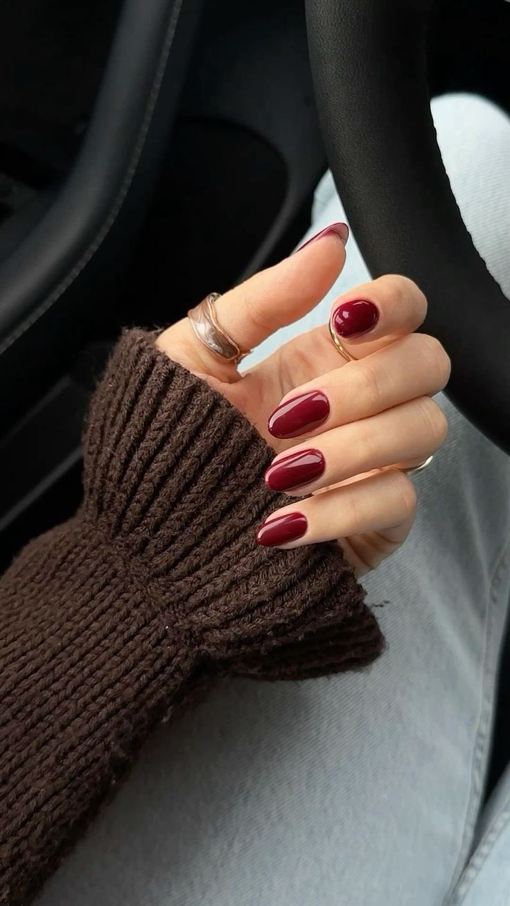 a woman's hand with red nail polish holding the steering wheel