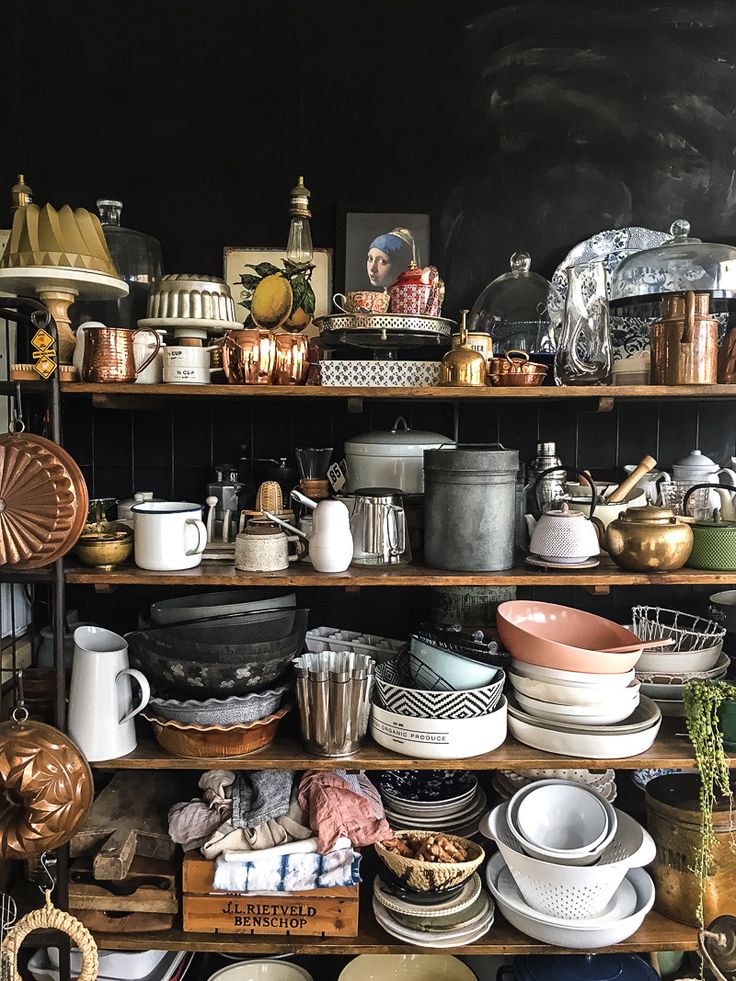 many pots and pans are on the shelves in this room, with one shelf full of dishes