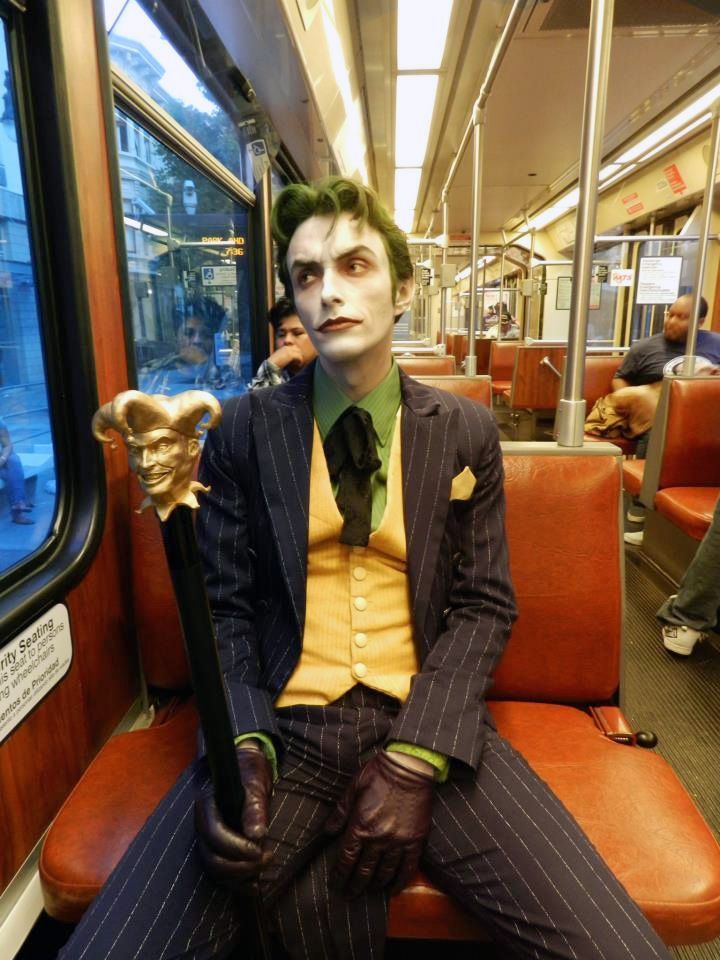 a man dressed as the joker sitting on a train