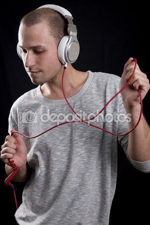 a young man listening to headphones while standing in front of a black background,